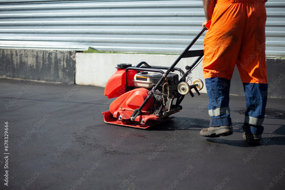 Obraz premium Asphalt paving machine. Worker compacts roadway. Repair of road.