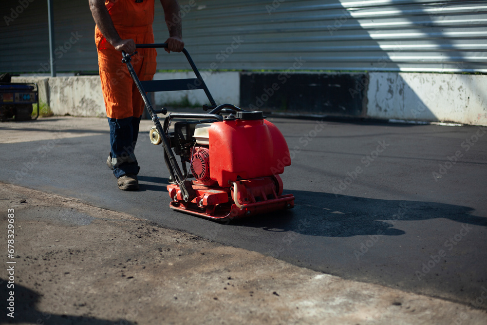 Obraz premium Asphalt paving machine. Worker compacts roadway. Repair of road.