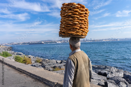 Istanbul, Turkey. November 3, 2023. Turkish street food vendor carries on his head large dish with rings of sesame bread 