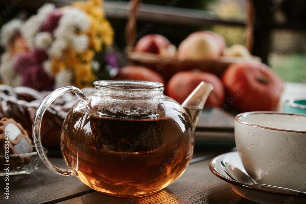 Black tea in a glass teapot on wooden table with fall decor Black tea in a glass teapot on wooden table with fall decor