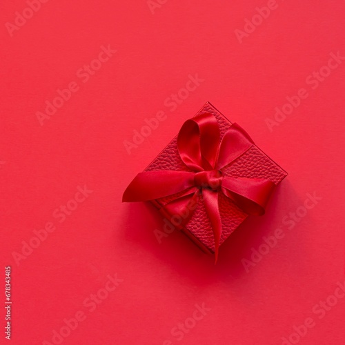 Red (scarlet) box (gift) on a red background. Festive concept, present for birthday, Christmas, Valentine's day, mothers Day.