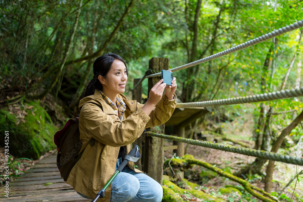 Fototapeta premium Woman use cellphone to take photo in forest hiking