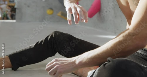 Slow motion closeup of a fit young man taping up his chalked hands and fingers during a climbing session in a bouldering gym photo