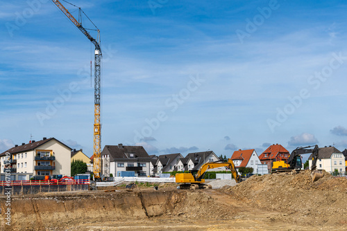 Earthworks before building construction. Excavators and tower crane at construction site. Residential buildings under in the background.