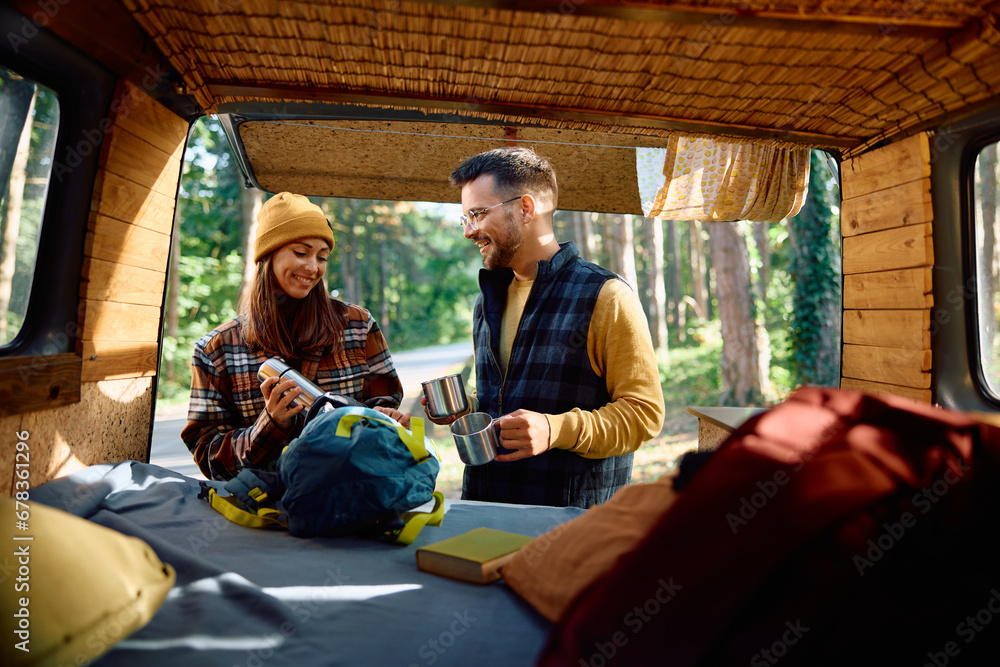 Happy couple of campers taking coffee break in their van in nature.