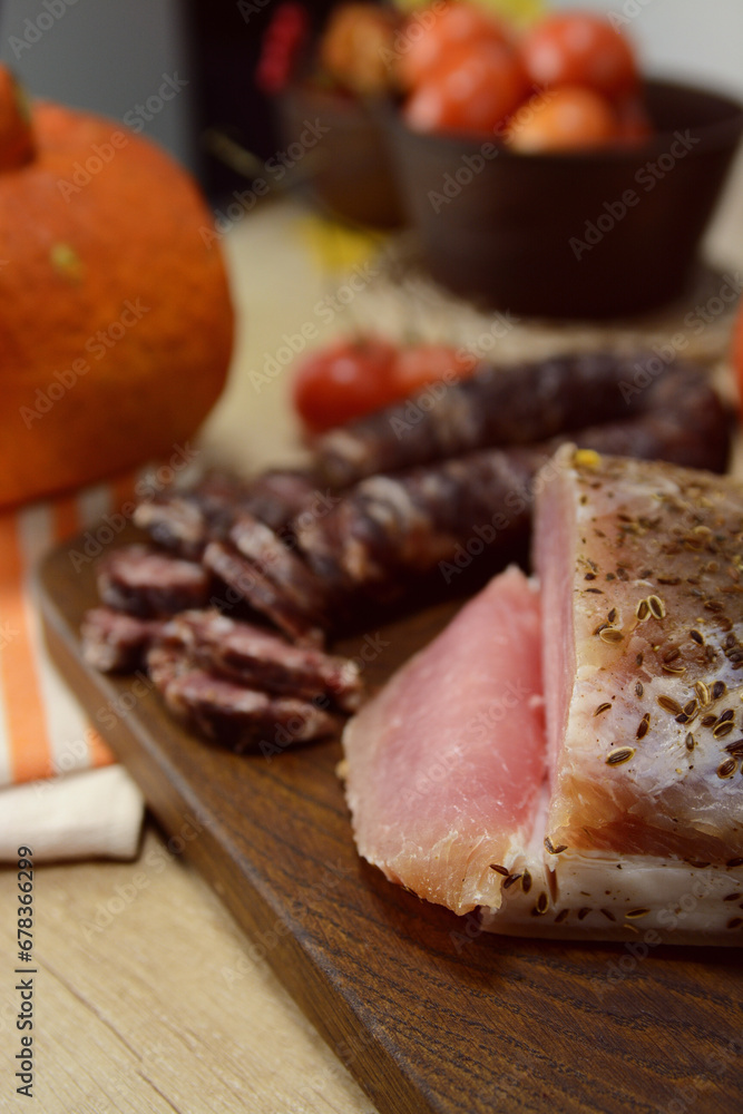 Homemade Chunks of salted bacon, pork lard , Dry salami sausage close-up on the wooden board with pumpkins on the background. Thanksgiving concept