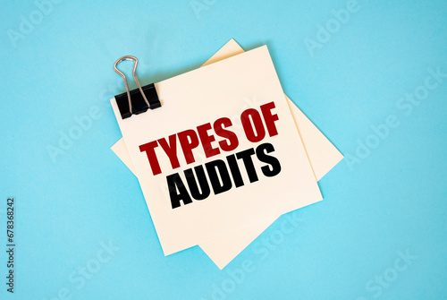 Text TYPES OF AUDIT on sticky notes with copy space and paper clip isolated on red background. Finance and economics concept.