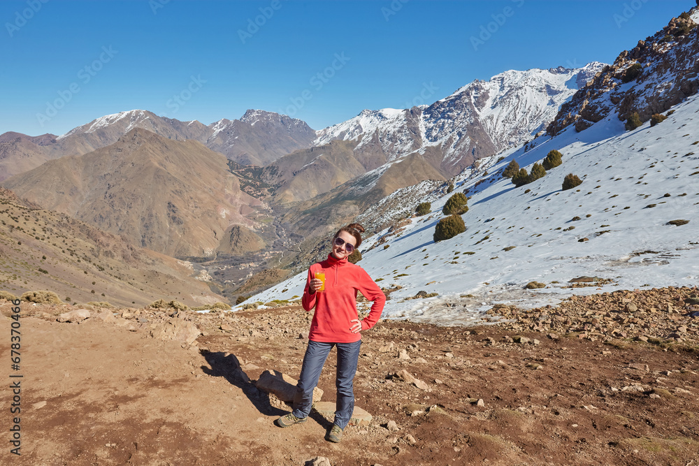 A tourist on the Atlas Mountains pass, with snow-capped peaks behind