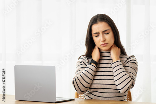 Sad tired young arab woman work at computer, suffer from pain in neck, health problems, feeling bad