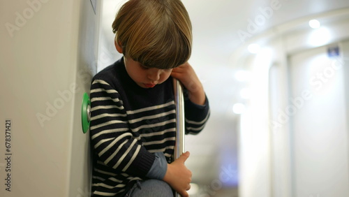 Fototapeta Naklejka Na Ścianę i Meble -  Little Boy Bored on Train Holding Metal Bar, child Playing Alone in Train Amidst Boredom inside public transportation