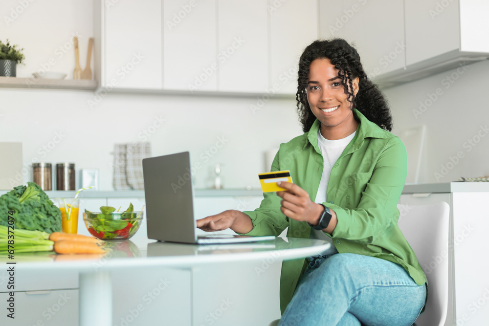 African woman ordering groceries with credit card and laptop indoor African woman ordering groceries with credit card and laptop indoor