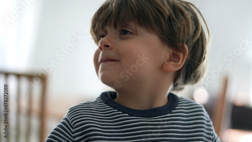 Little boy shaking head in negation while smiling, portrait close-up face of happy child saying NO with body language refusing offer photo