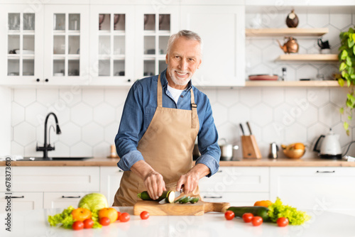 Portrait of happy senior man cooking food in kitchen at home