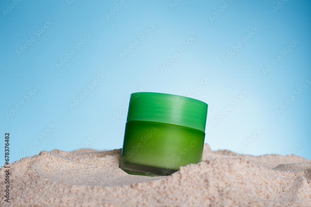 Jar of moisturizer cream with apple extract on sand against blue background. Space for text Jar of moisturizer cream with apple extract on sand against blue background. Space for text