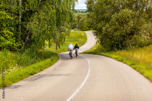 rowerzyści jadący krętą drogą na wsi