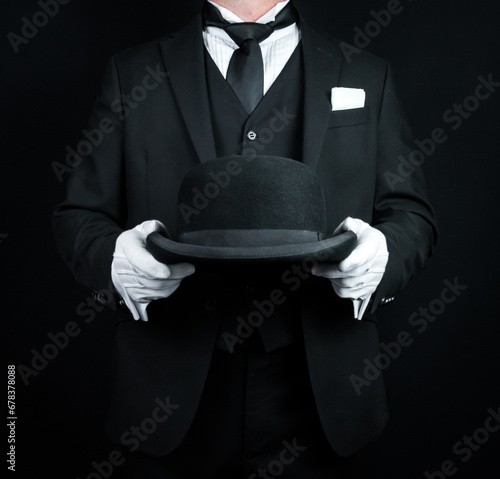 Portrait of Butler in Dark Formal Suit and White Gloves Holding a Bowler Hat. Concept of Service Industry and Professional Courtesy.