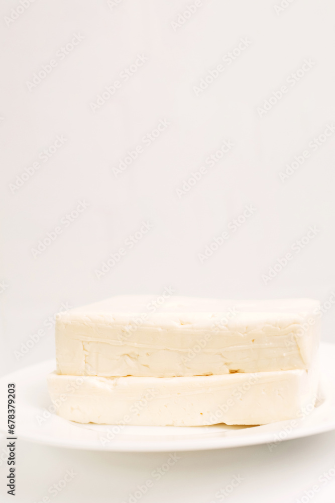 Feta cheese in a white plate on a white background.