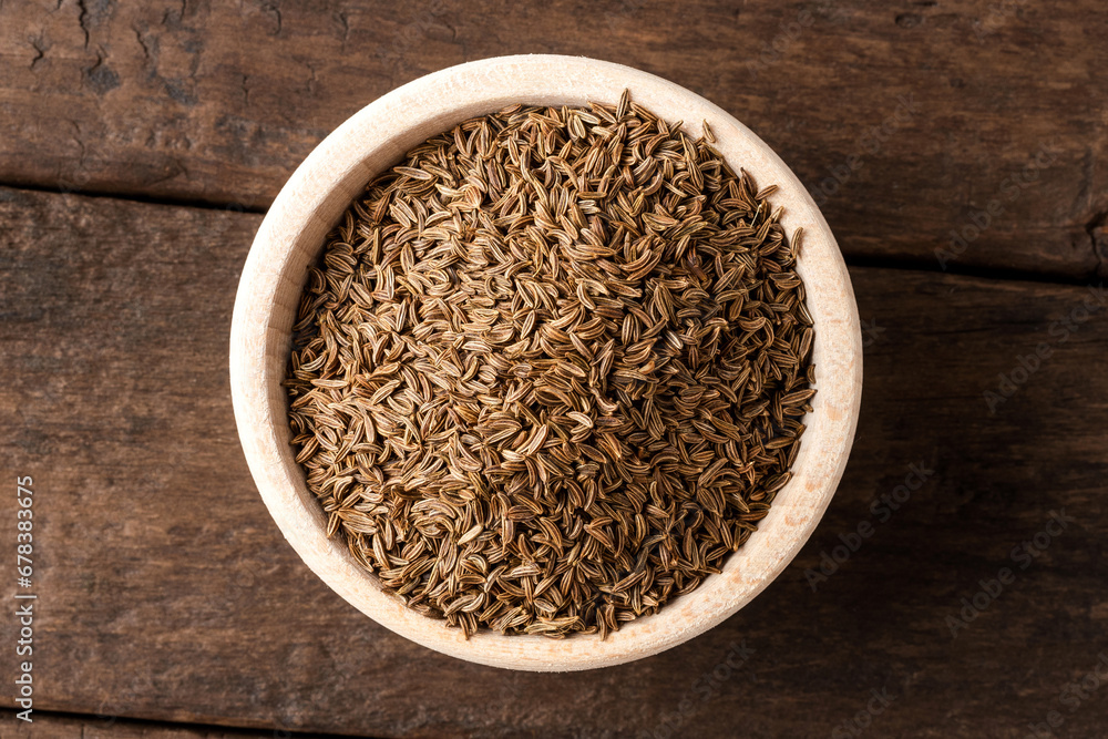 Dried cumin in bowl on wooden table. Close up. Top view Dried cumin in bowl on wooden table. Close up. Top view