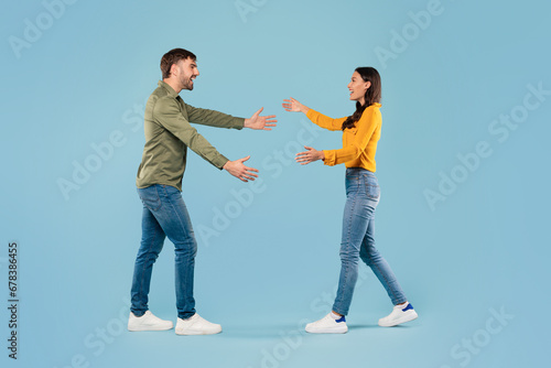 Playful couple reaching for hug, side view