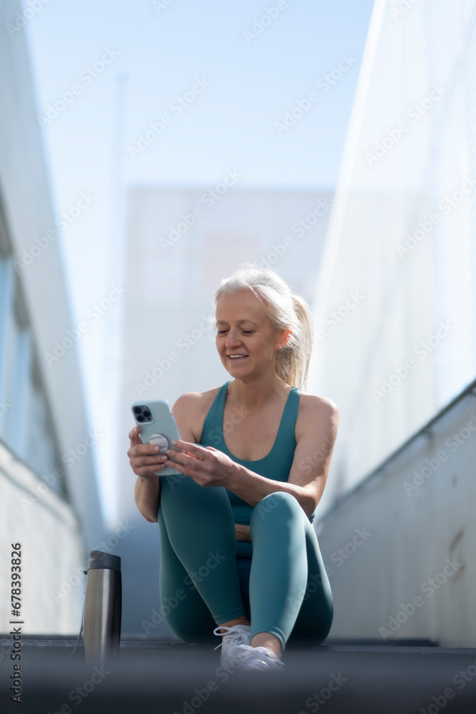 Active senior woman taking a break to check her phone outdoors Active senior woman taking a break to check her phone outdoors
