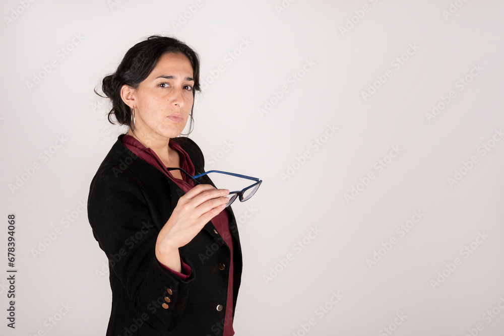Brunette latin business woman wearing a black suit on white studio background looking seriously at the camera Brunette latin business woman wearing a black suit on white studio background looking seriously at the camera