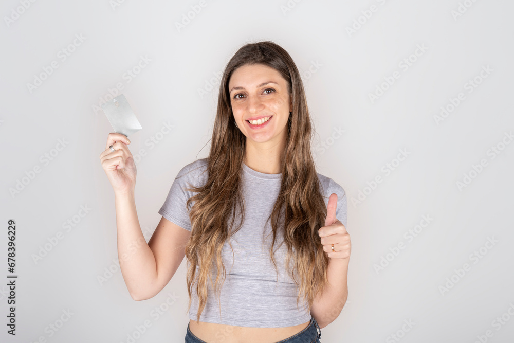 Smiling young blond latin american woman 20s in gray casual clothes isolated on white background studio portrait. People sincere emotions lifestyle concept. Copy space. Hold credit bank card. Smiling young blond latin american woman 20s in gray casual clothes isolated on white background studio portrait. People sincere emotions lifestyle concept. Copy space. Hold credit bank card.