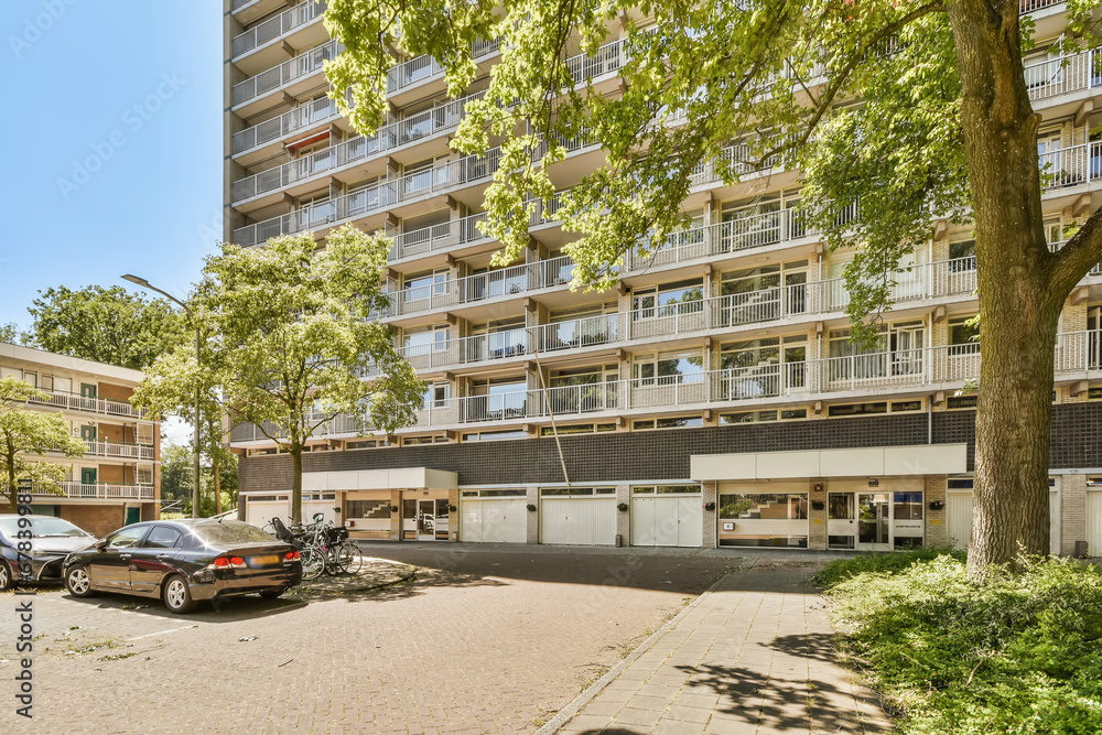 an apartment building with cars parked in the parking lot next to it and some trees on either side of the street an apartment building with cars parked in the parking lot next to it and some trees on either side of the street