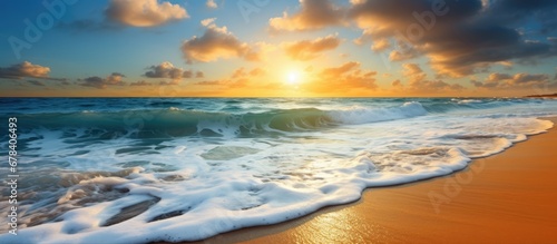 The breathtaking summer landscape of the beach with its azure blue sea golden sandy shores and vibrant orange hues of the setting sun against a backdrop of clear blue skies and fluffy white