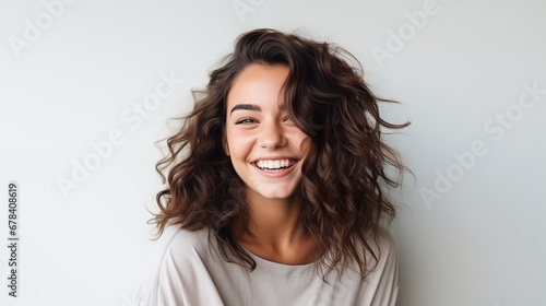  Portrait of a young and beautiful brunette woman on white background, smiles and laughs to the camera. Advertising concept.