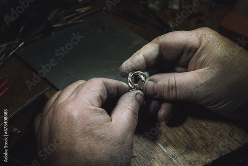 master of jewelry with an earring. Working desk for craft jewelry making with professional tools. Sapphire diamond ring on the jeweler's desktop © alina