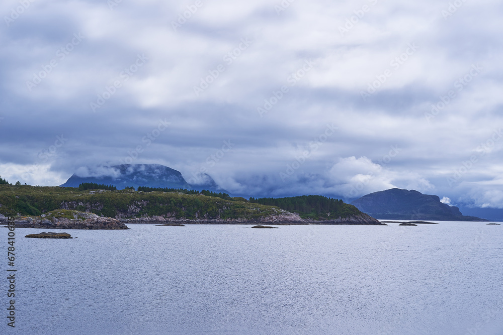 Landscape picture of the dramatic scandinavian coast of norwegian sea on the island Otroya in the middle of Norway. Picture is taken during beautiful summer calm and cloudy sunset in the blue hour.