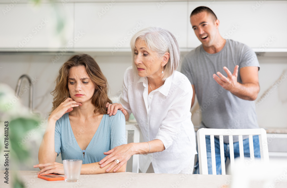 Obraz premium Family of three - mother-in-law, daughter and son quarreling in kitchen