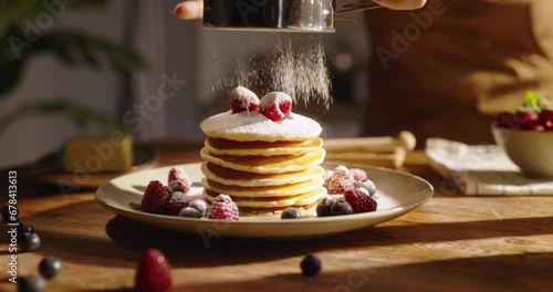 American traditional breakfast on kitchen background. Unknown sprinkles powdered sugar on pancake pancakes with berries. Advertising. Little celebration of taste for weekend morning. Gluten-free photo