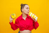 regnant woman eats sweet donuts on a yellow background. A pregnant woman in a pink shirt and glasses eats a sweet cake. Harmful food during pregnancy.