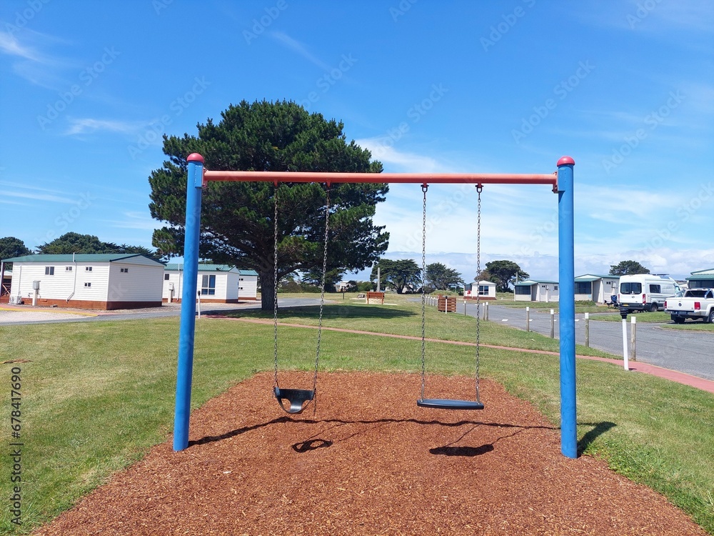 Swinging games in the park for kids with rural houses under blue sky in Devonport, Tasmania Swinging games in the park for kids with rural houses under blue sky in Devonport, Tasmania