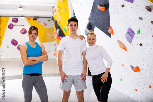 Group photo of women and young man standing in bouldering gym at climbing wall.