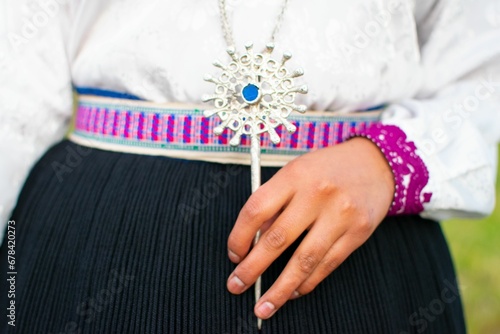 Traditional Saraguro women's silver jewelry in a woman's hand with a blue stone on its center photo