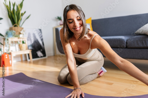 Young fit woman unrolling yoga mat to meditate or do workout exercises routine at home. Healthy lifestyle and sport concept.