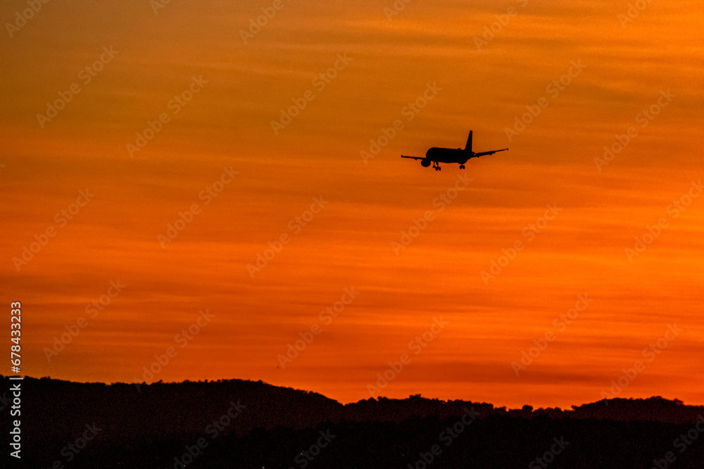 Avion en vol dans un ciel orange au coucher de soleil 