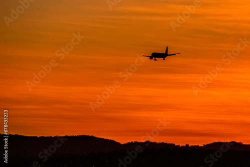 Avion en vol dans un ciel orange au coucher de soleil  © Bernard