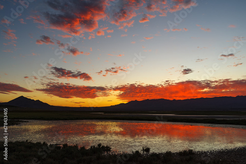 Red clouds at dusk reflected in a transient desert pond in Tecopa, California. 