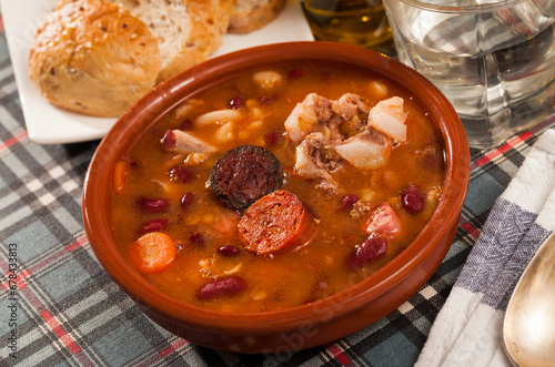 Traditional Asturian rich beans stew with pork shoulder, morcilla and chorizo (Fabada) served in clay bowl