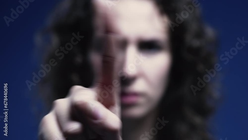 Upset woman pointing finger to camera saying NO by waving in rejection. Close-up of negative body language gesture photo