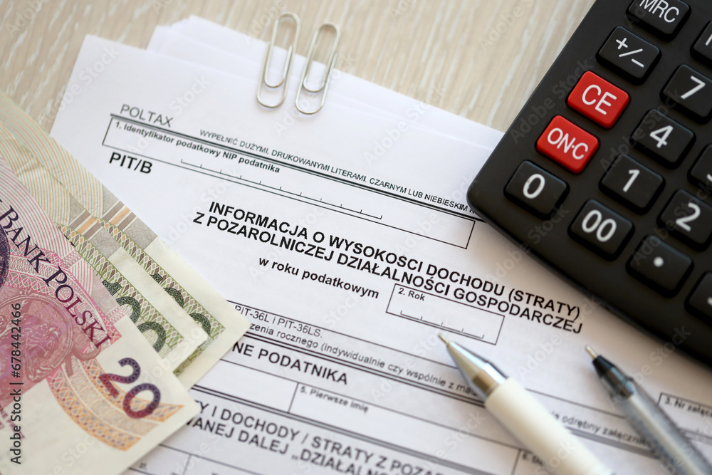 Information on amount of income or loss from non-agricultural economic activity, PIT-B form on accountant table with pen and polish zloty money bills close up Information on amount of income or loss from non-agricultural economic activity, PIT-B form on accountant table with pen and polish zloty money bills close up