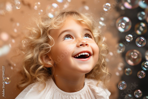 Happy blonde little girl excited looking up in the bubbles