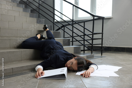 Bild auf Leinwand Unconscious woman with scattered folder and papers lying on floor after falling
