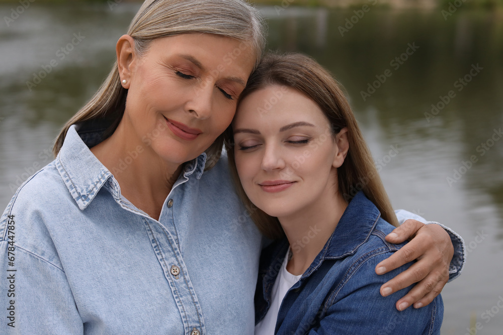 Happy mature mother and her daughter near pond Happy mature mother and her daughter near pond