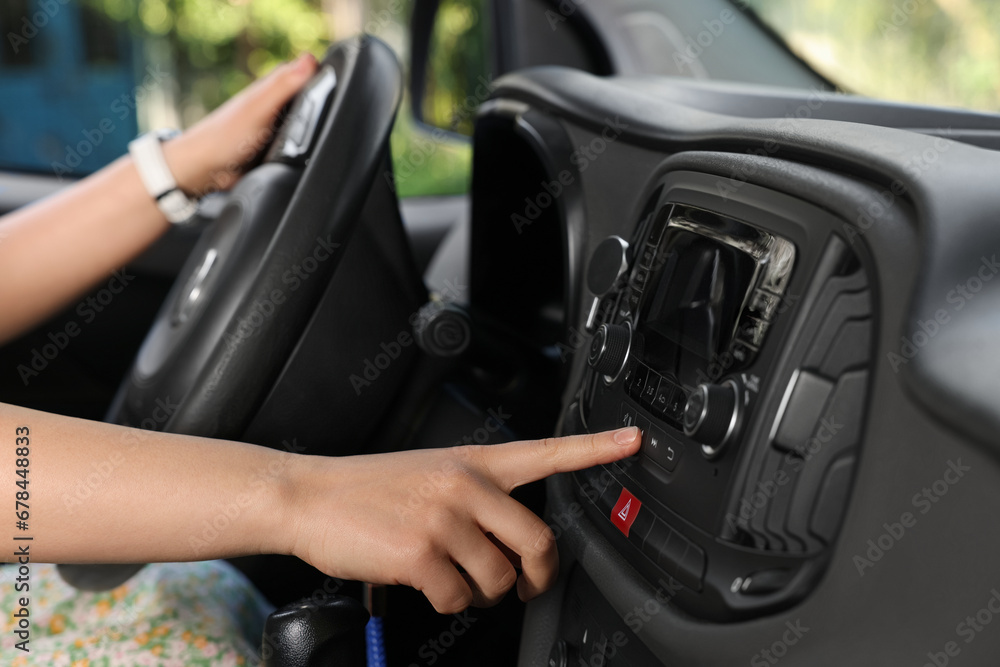Naklejka premium Choosing favorite radio. Woman pressing button on vehicle audio in car, closeup
