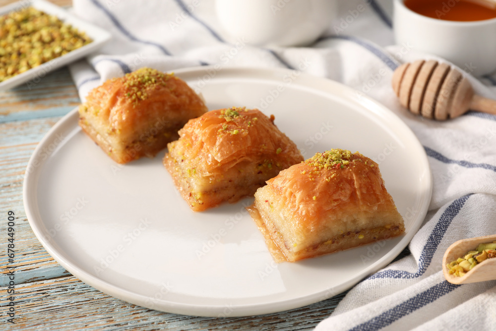 Delicious sweet baklava with pistachios on light blue wooden table, closeup