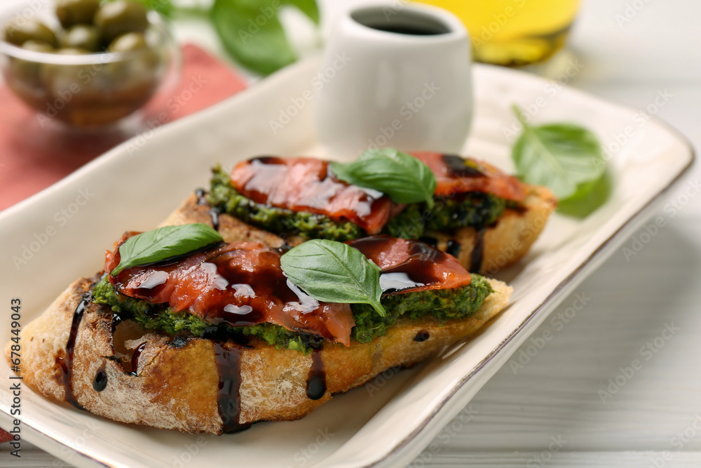 Delicious bruschettas with balsamic vinegar and toppings on white wooden table, closeup